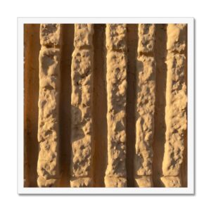 20x20 inch framed photograph of deep vertical grooves on a sunlit wall set in a white frame.