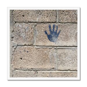 Photo of a child’s blue handprint left behind on a cinder block wall mounted and framed.