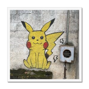 Framed picture of a Pokemon character Pikachu painted on a concrete wall beside electrical box.