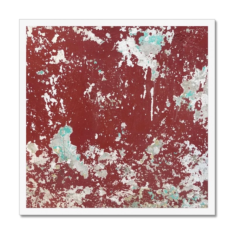 Peeling layers of blood red paint on a concrete wall mounted in 20x20” white frame for hanging.