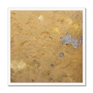 Framed picture of weathered yellow paint on a concrete wall with shadows and imperfections that depict the peel of a plantain fruit.