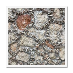 Framed 20x20 photo of a stone wall with small flat rocks stuffed into the mortar like barnacles.