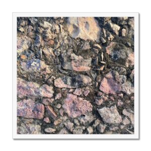 A 20x20” white-framed close-up of a wall of multi-colored, rough-hewn stones.