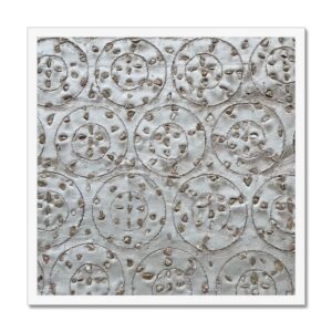 Funky geometric yoyo patterns of small stones inlaid on a concrete wall in a white 20x20 white frame.